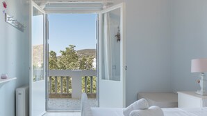 Ein Schlafzimmer mit Balkon, einem Bett, einem Nachttisch und Blick ins Freie.