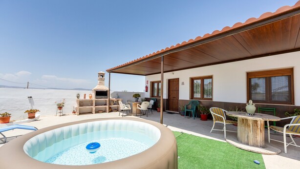An outdoor pool area with a hot tub, a covered patio with chairs, and a view of the sea. - Casa Inés rural: 1 habitación, vistas a la montaña, Wi-Fi y aire acondicionado (Fernán Pérez)