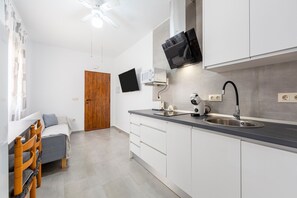 Une cuisine moderne équipée d’un four à micro-ondes encastré, d’un téléviseur à écran plat, d’un évier et d’un ventilateur de plafond.