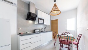 Una cocina moderna con armarios blancos, un microondas y un comedor con mesa y sillas.