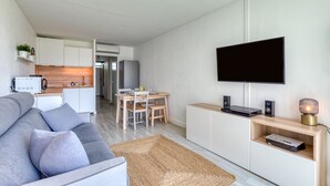Ein modernes Wohnzimmer mit einer Couch, einem Fernseher und einer Unterhaltungseinheit.