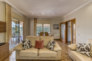 Un salón espacioso con un sofá color beige, una mesa de centro de madera y una zona de comedor con sillas.