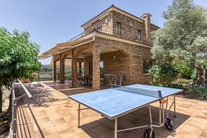 Una casa con cancha de tenis, mobiliario de exterior y zona de patio.