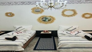 A hotel room with two beds, a chandelier, and decorative mirrors on the walls.