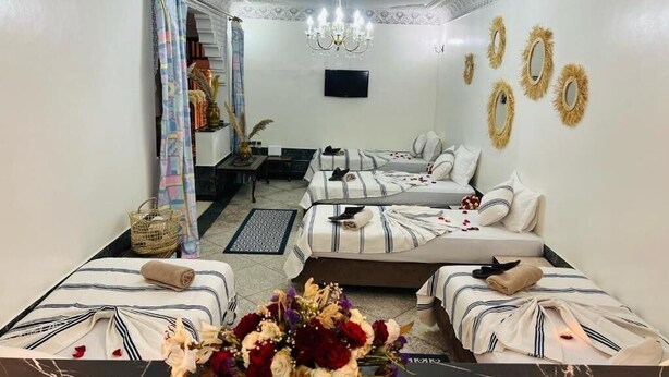 A hotel room with a bed, a sofa, a TV, and a decorative wall.