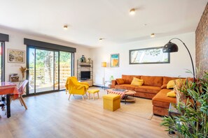 Un salon moderne comprenant un canapé, un fauteuil, une table basse et un coin repas avec une table et des chaises.