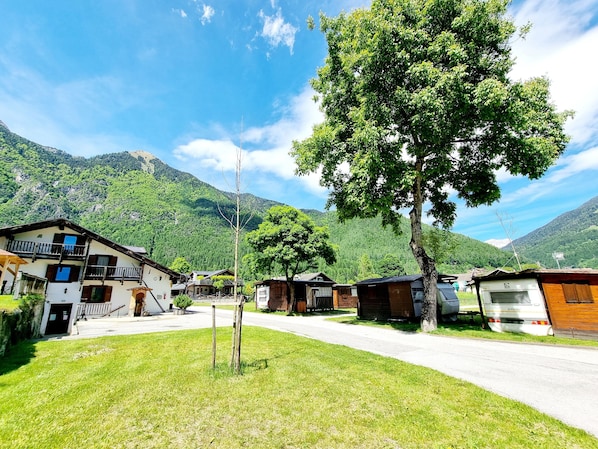 Un village rural avec des maisons traditionnelles, un ciel dégagé et des montagnes en arrière-plan.