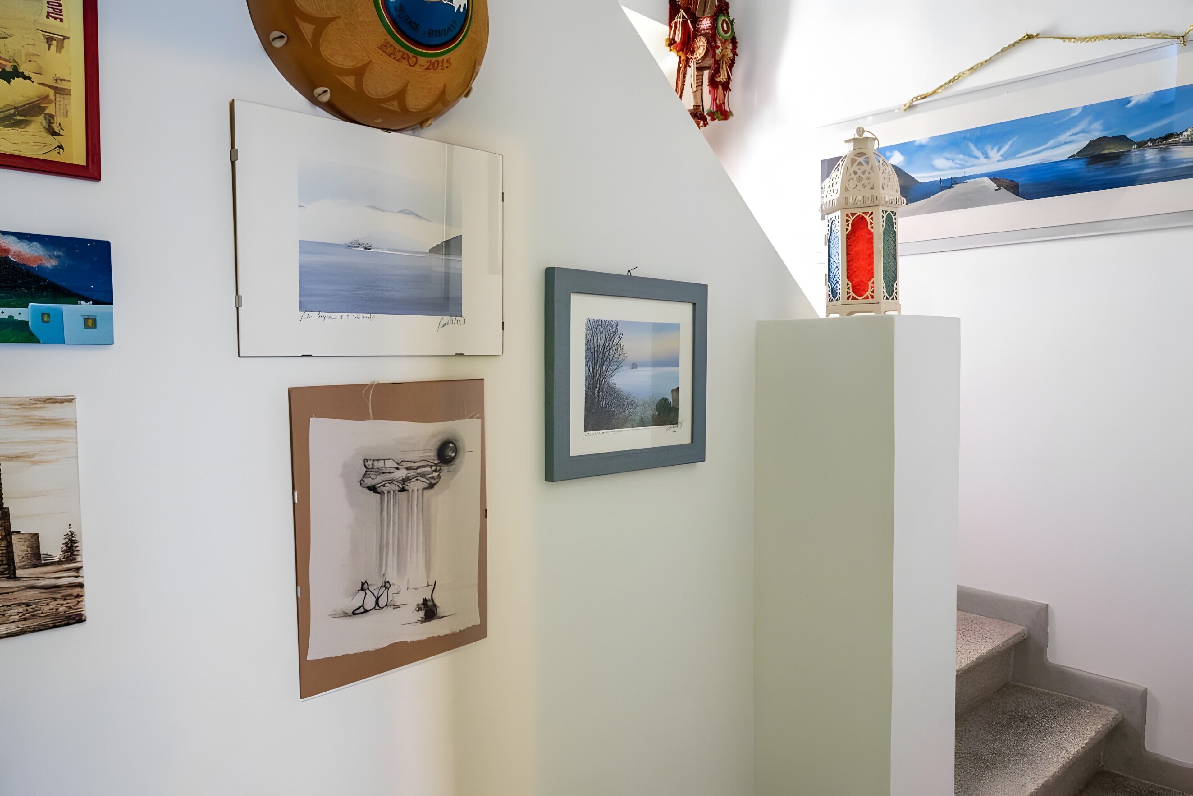 Un escalier orné d’un tableau encadré au mur, une lanterne décorative et une œuvre d’art encadrée.
