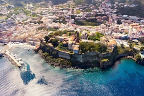 An aerial view of a coastal town with a prominent fortified structure, a marina, and a dense urban area with buildings. - Room 'Verde' with Shared Terrace, Wi-Fi and Air Conditioning (Lipari)