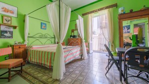 Una habitación con cama, una silla, una mesa y una ventana con cortinas.