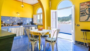 Un interior amarillo y luminoso con cocina, comedor y amplios ventanales.