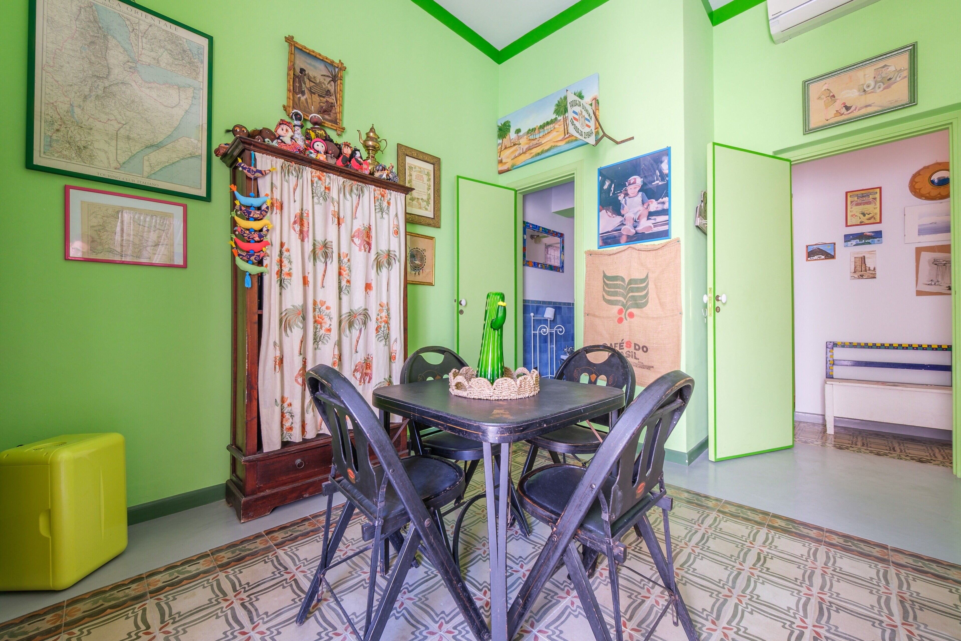 A dining area with a table, chairs, and a green wall with various decorations.