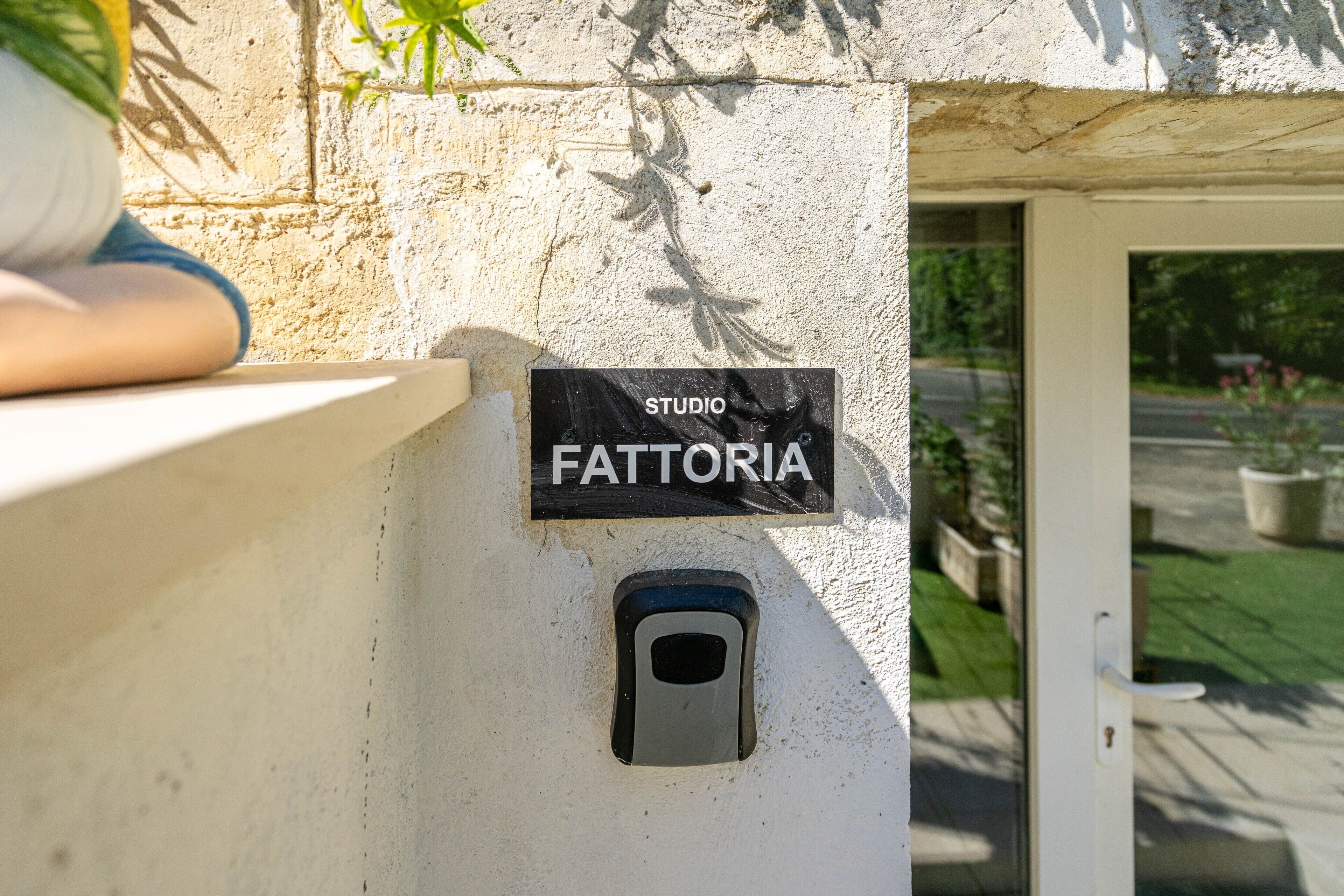 A sign reading 'STUDIO FATTORIA' on a wall, a small window, and a door leading outside.