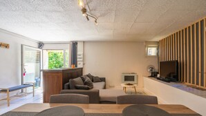 Ett modernt vardagsrum med en soffa, ett matbord med bordsunderlägg, en tv och ett litet sidobord.