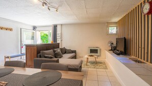 Ett modernt vardagsrum med en soffa, en tv, ett träskåp och en matplats med ett bord och stolar.