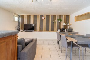 Eine moderne Küche mit Essbereich, einer Couch und einem Fernseher.