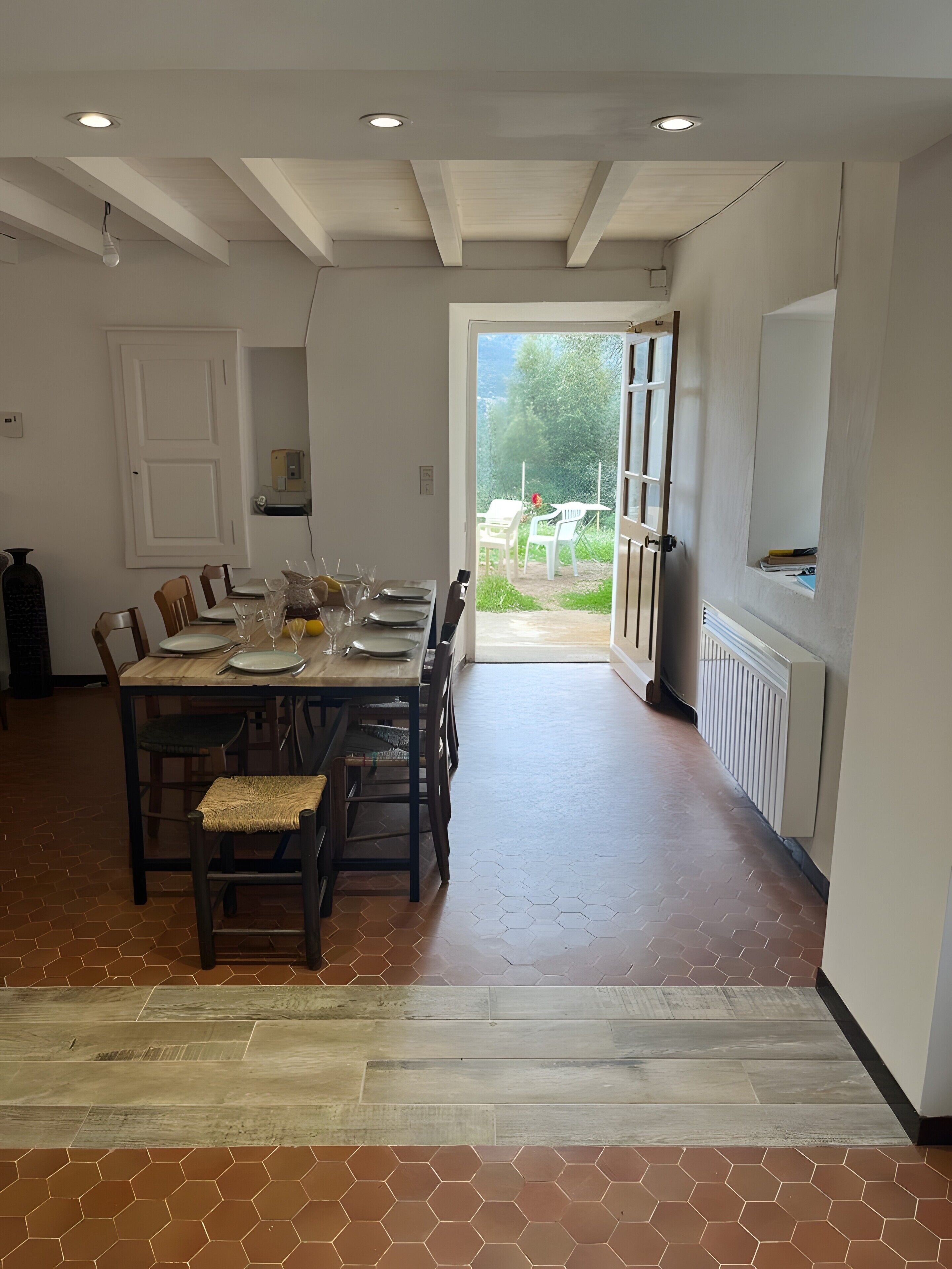 A dining area with a table set for four, a radiator, and a view of the outdoors.