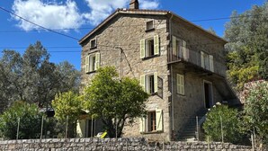 Un bâtiment en pierre doté de nombreuses fenêtres, d’un balcon et d’une cheminée.