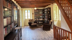 Une pièce spacieuse avec un escalier en bois, une bibliothèque et deux fauteuils.