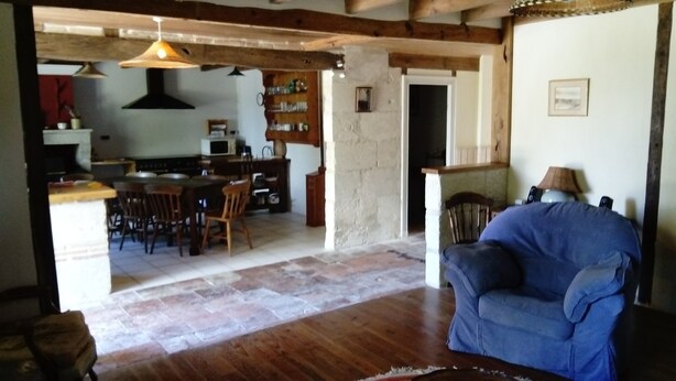 A spacious living area with a blue sofa, wooden flooring, and a kitchen in the background. - Porcherat - Perigord Vert, Dordogne: Lake View, Private Garden & Wi-Fi (La Roche-Chalais)