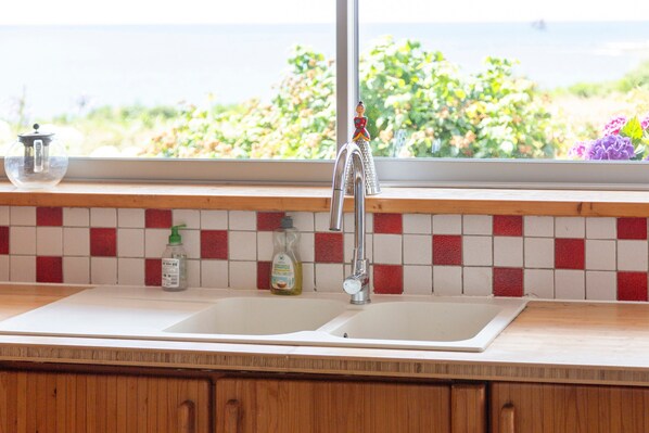 A kitchen with a double sink, a window with a view of greenery, and a tiled backsplash. - Large contemporary villa, right on the water... (Audierne)