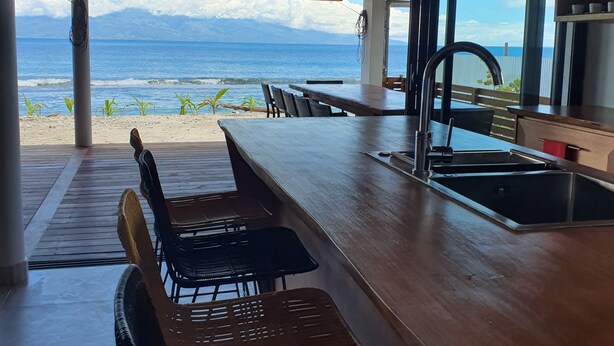 Une cuisine moderne dotée d’un grand îlot central, d’un évier et offrant une vue sur l’océan.