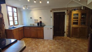 A kitchen with wooden cabinets, a dishwasher, a coffee maker, and a tiled floor.