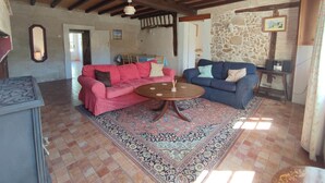 A cozy living room with two sofas, a patterned rug, and a stone wall.