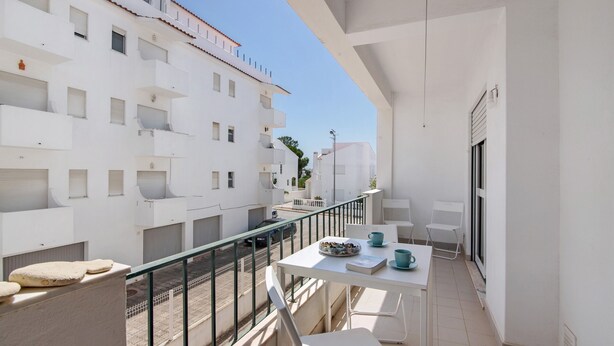 A balcony with a white table, chairs, and a small seating area. - Apartment 'Excellent  In Olhos D´Água' with Balcony, Wi-Fi and Air Conditioning (Olhos de Água)