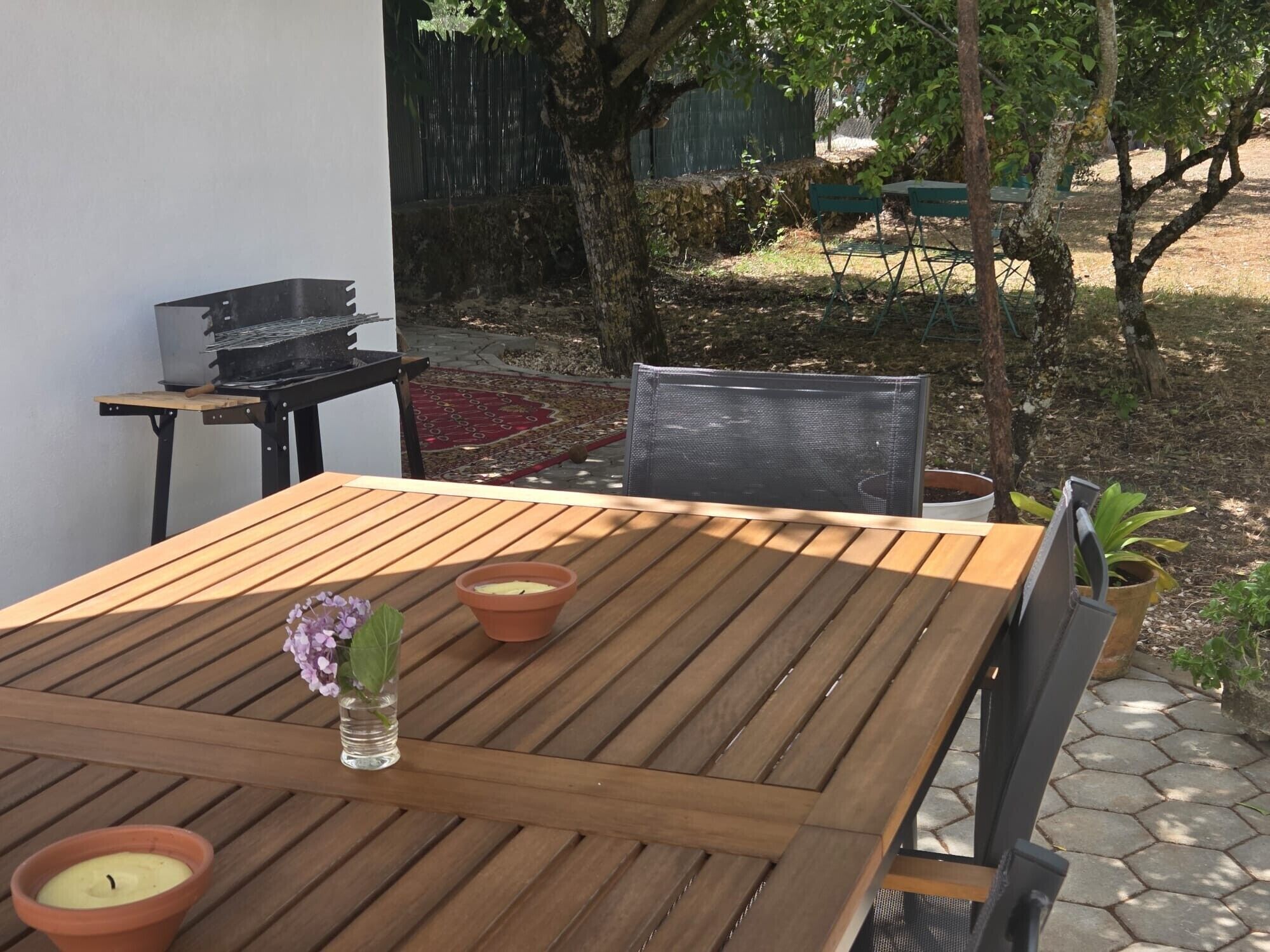 Ein Holztisch mit zwei Terrakotta-Kerzen und einer kleinen Vase mit Blumen.
