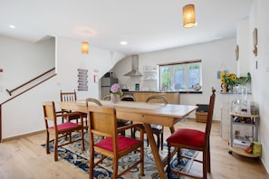 A dining area with a wooden table and chairs, a kitchen in the background, and a staircase. - Room 'Santo Agostinho' with Shared Terrace, Shared Garden and Wi-Fi (Fátima)