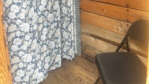 A wooden cabin with a floral curtain and a chair. - Charming A-frame cabin set in the woods overlooking deep wooded ravines. (Charleston)