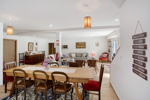 A dining area with a wooden table, chairs, and a hanging sign with room names.