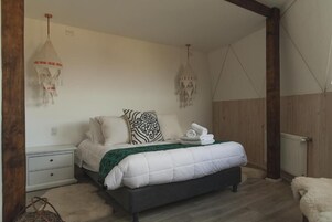Un dormitorio con cama, mesitas de noche y lámparas colgantes.