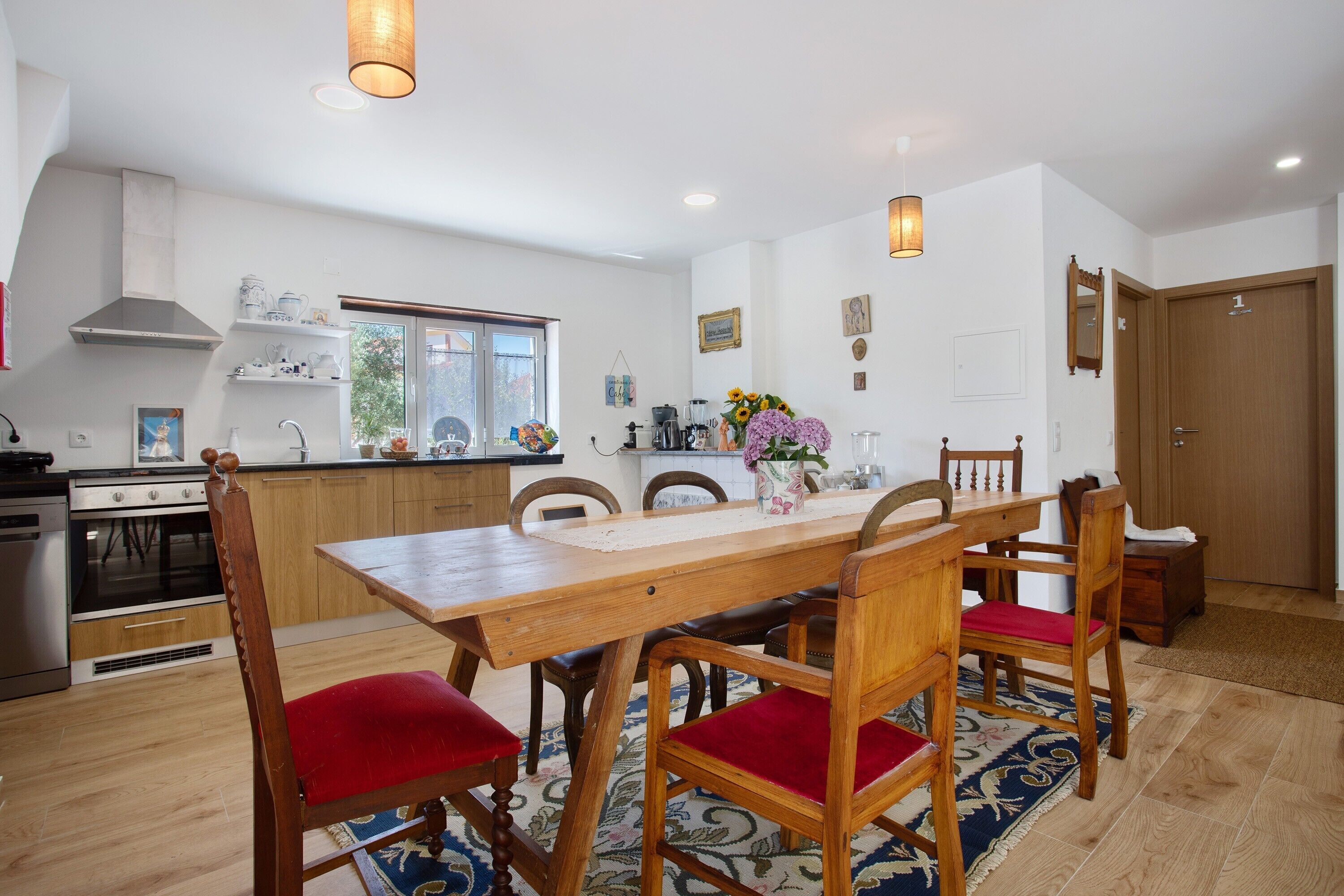 Een moderne keuken met houten kastjes, een centraal eiland en een zithoek met een houten tafel en stoelen.