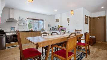 Een moderne keuken met houten kastjes, een centraal eiland en een zithoek met een houten tafel en stoelen.