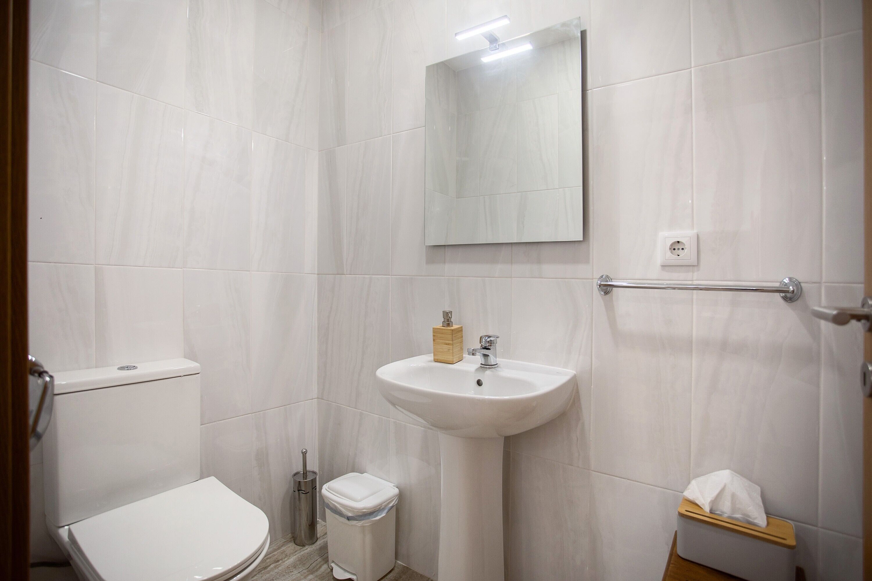 Een badkamer met toilet, wastafel, spiegel en handdroger.