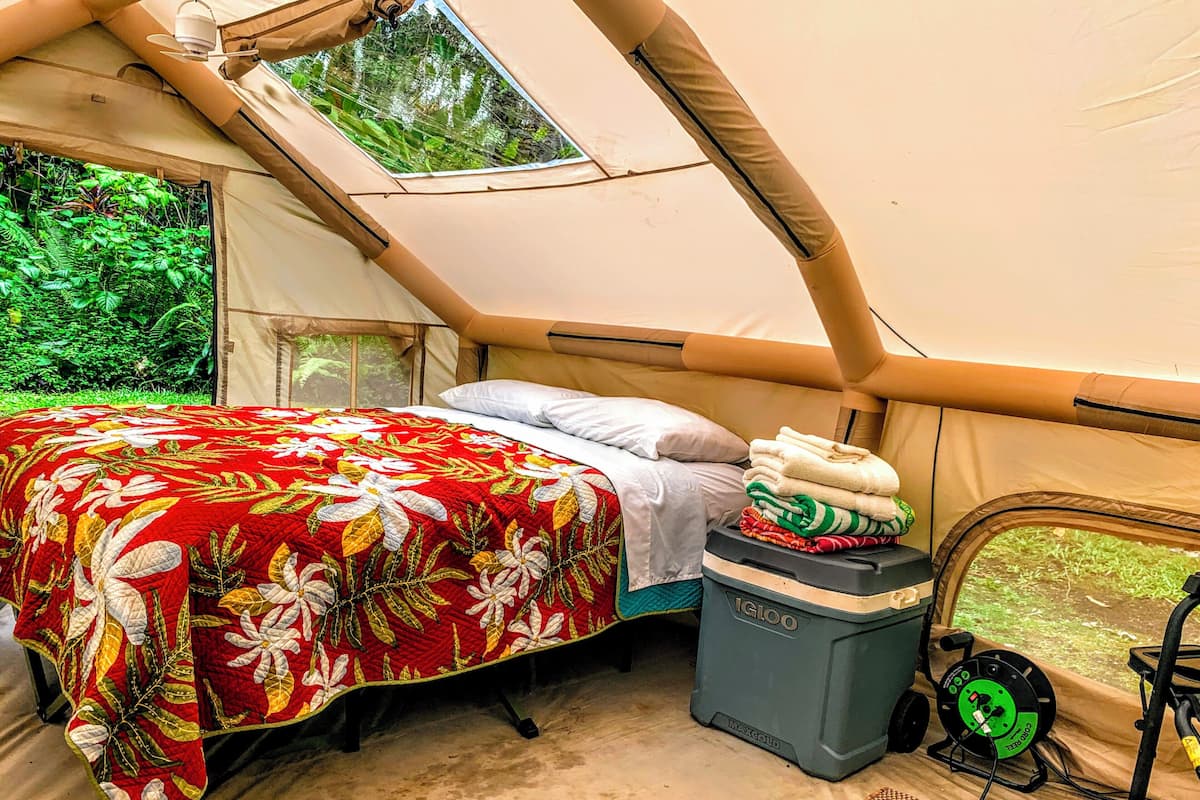 A tent with a bed, a small table, and a window.