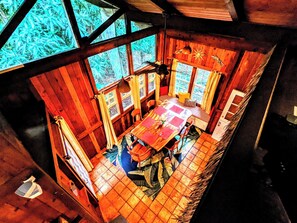 A wooden cabin with a dining area, large windows, and a ceiling fan. - Kehena Mauka Nui LGBTQ Clothing Optional (Pahoa)