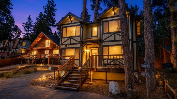 A two-story lodge with a staircase leading to the entrance, surrounded by trees. - Mama Bear's Cottage (Big Bear Lake)