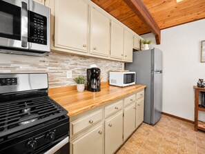 A kitchen with a stainless steel stove, a microwave, a coffee maker, and a refrigerator. - Mama Bear's Cottage (Big Bear Lake)