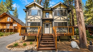 A two-story lodge with a central entrance, wooden railings, and a stone pathway leading to the door. - Mama Bear's Cottage (Big Bear Lake)