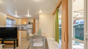 Un espace de vie compact comprenant un coin cuisine, un espace repas avec un banc et un téléviseur.