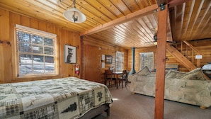 Een gezellig kamer in chaletstijl met een groot bed, een eettafel en een bank.