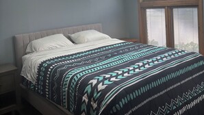 Un dormitorio con tragaluz, cama con ropa de cama estampada y vista a la montaña.