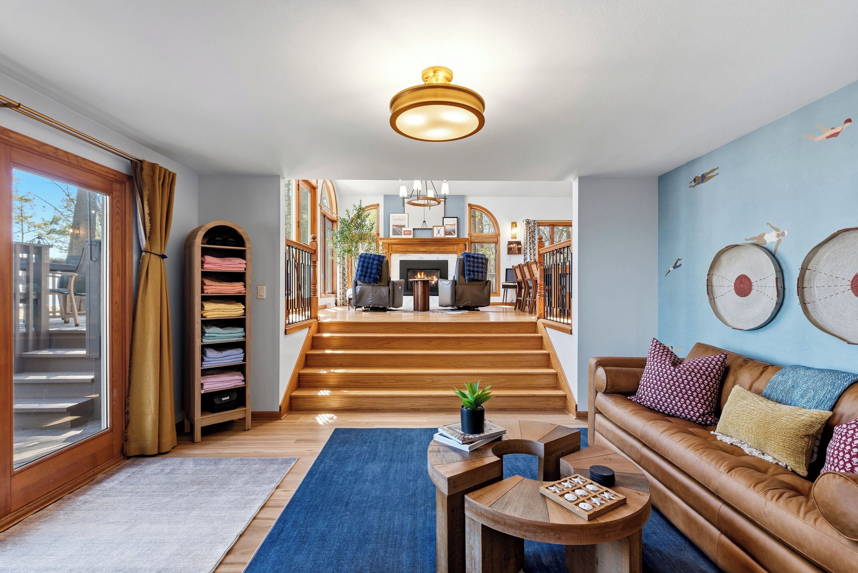 Un vaste espace de vie comprenant un canapé en cuir, une table basse en bois et un escalier menant à une salle à manger.