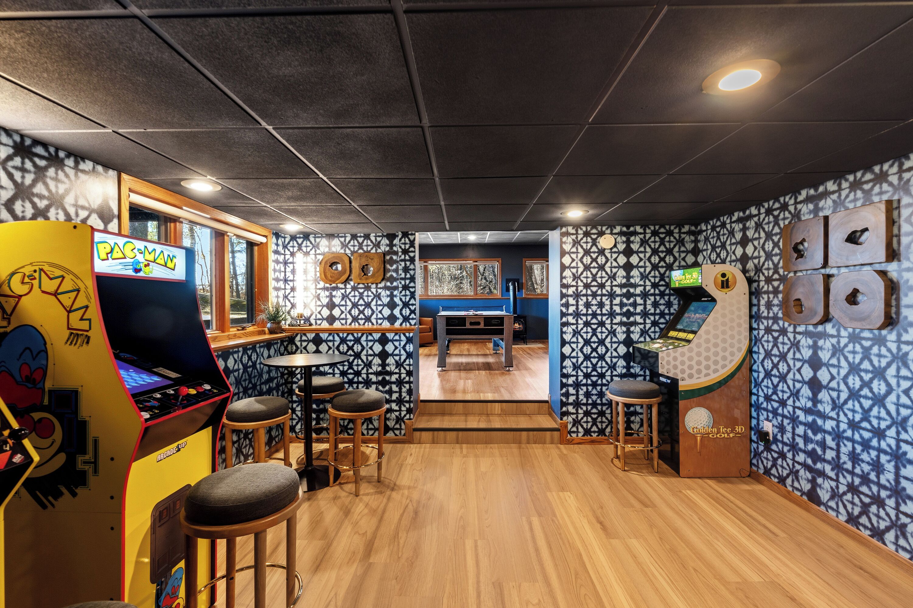 A bar area with arcade games, stools, and a patterned wall.