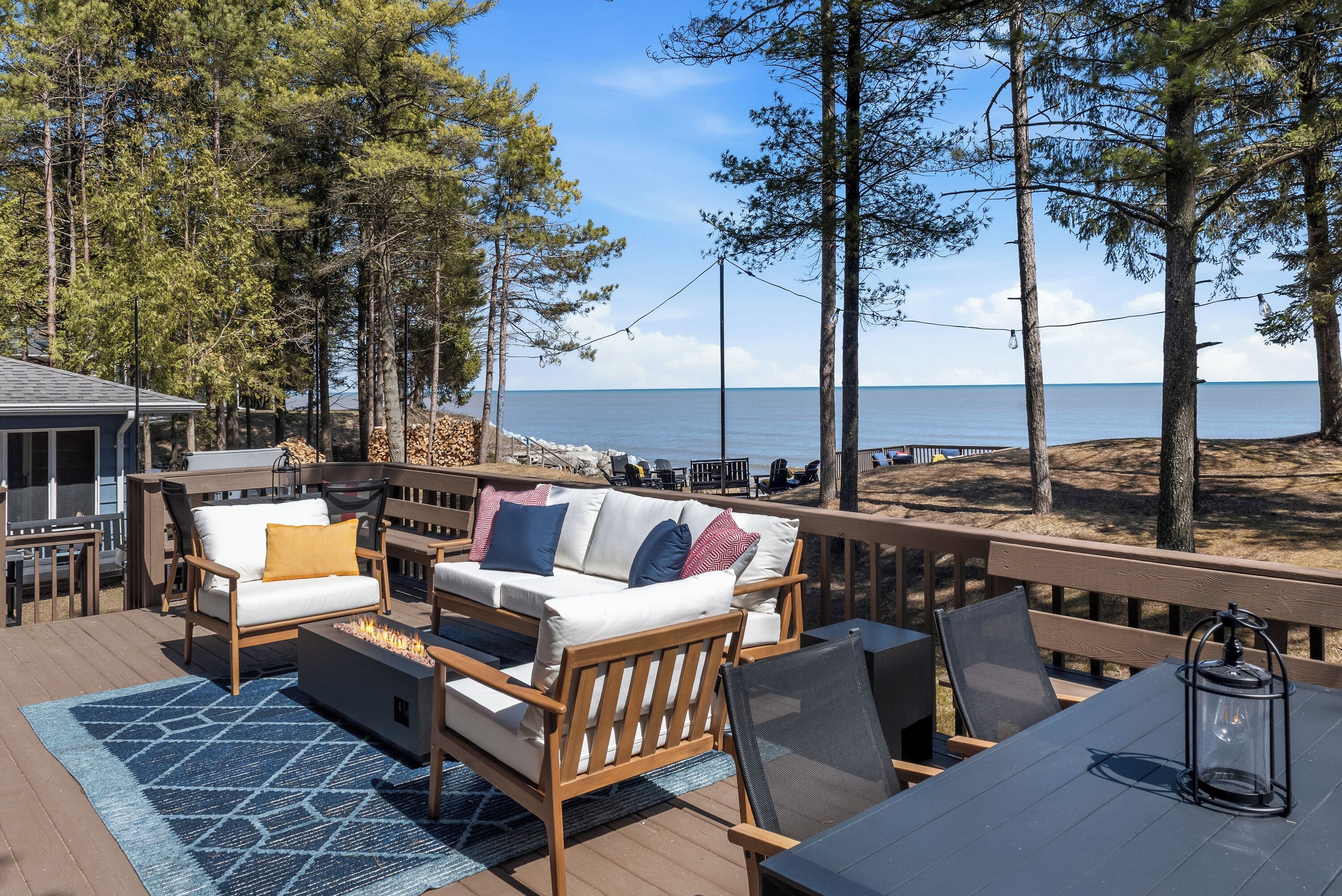 A deck with outdoor furniture, a view of the sea, and a wooden railing.