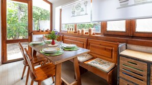 A wooden dining area with a table set for four, benches, and a window with potted plants. - Lu Nibbaru di Portobello by Interhome (Portobello)