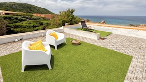 A rooftop terrace with white lounge chairs and a view of the sea. - Lu Nibbaru di Portobello by Interhome (Portobello)